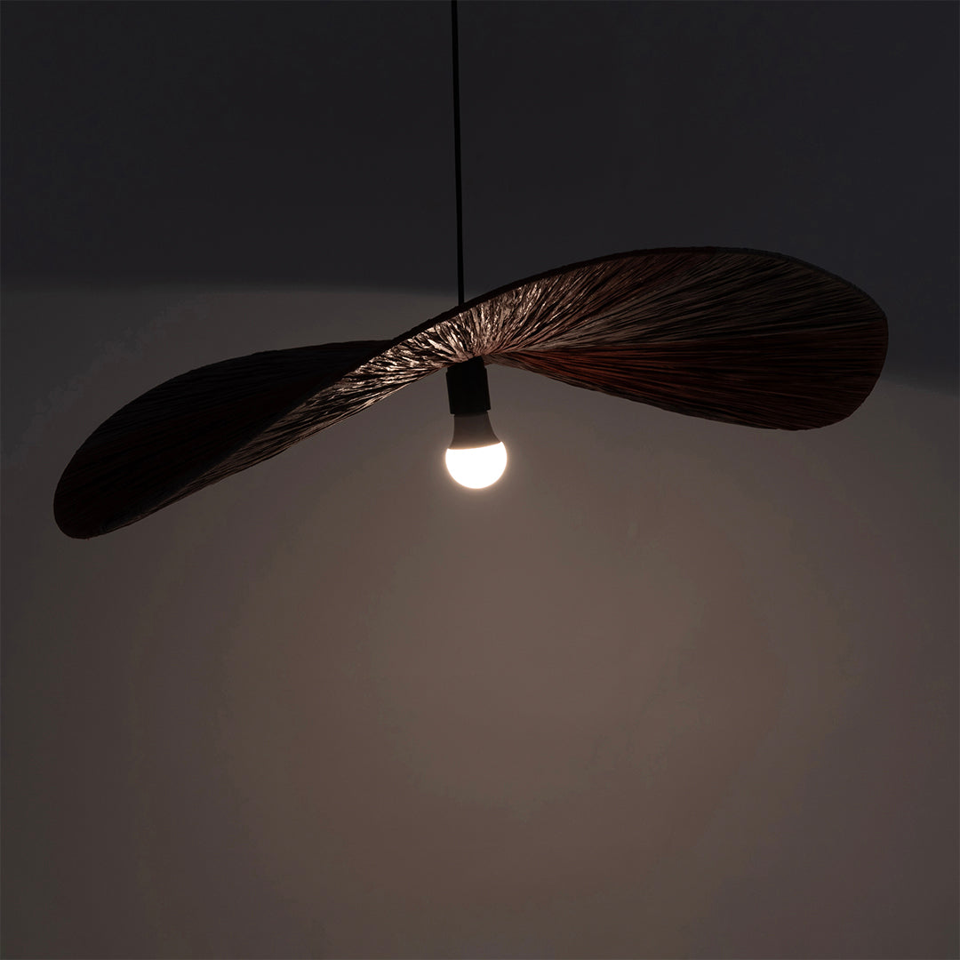 Dual colour Raffia Pendant Lamp illuminated, showing the curved shade in silhouette around a glowing bulb.