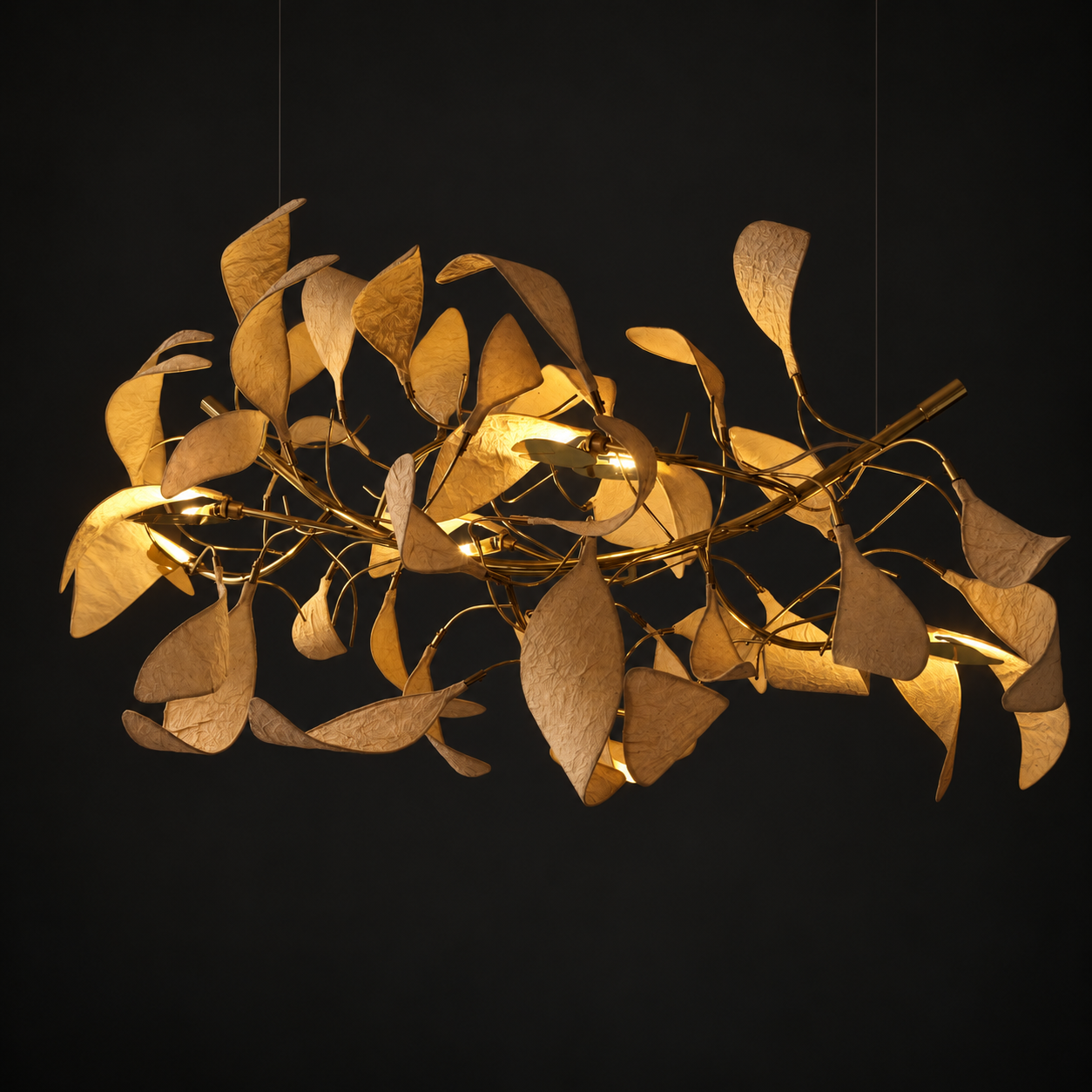Arbor Chandelier illuminated against a dark background, with leaf-like paper forms and a brass frame.