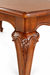 Close-up of Louis Dining Table No.5, showing carving on a walnut-finished table leg and the curved apron.