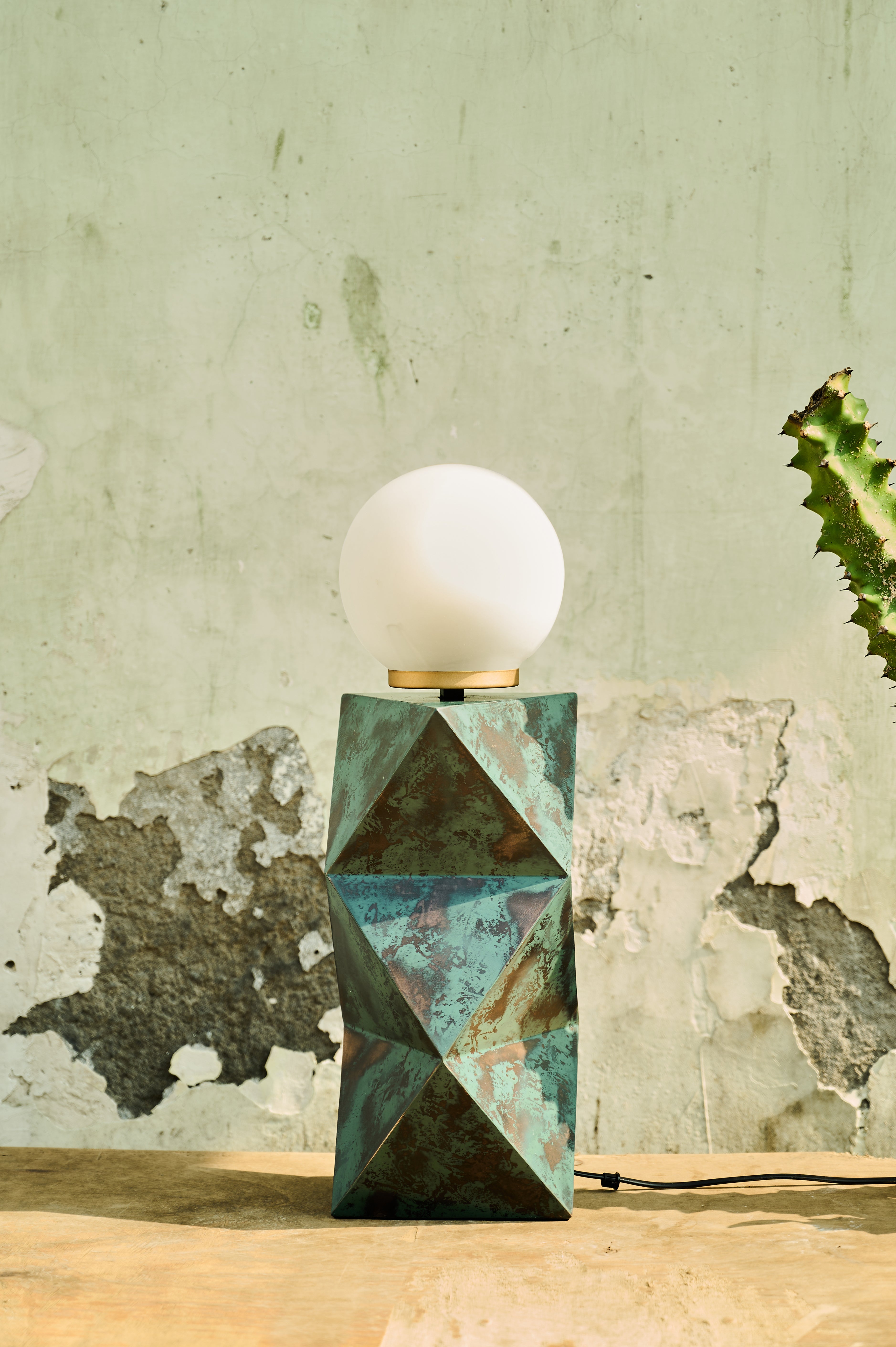Facet Table Lamp with a white globe shade on a wooden surface