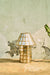 Brass-Aged Table Lamp full view beside a textured wall