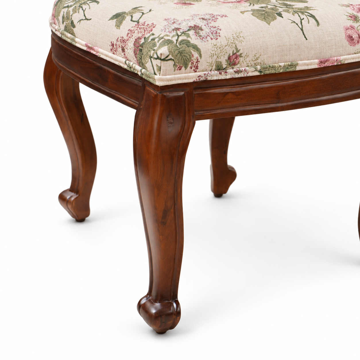 Leg detail of Louis Dining Chair No.5 showing the curved walnut-finished mango wood leg and the edge of the floral upholstered seat.