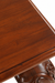 Close-up of Louis Dining Table No.5, showing the wood grain and shaped edge of its walnut-finished top.