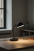 Black desk lamp on a wooden surface with a blurred background