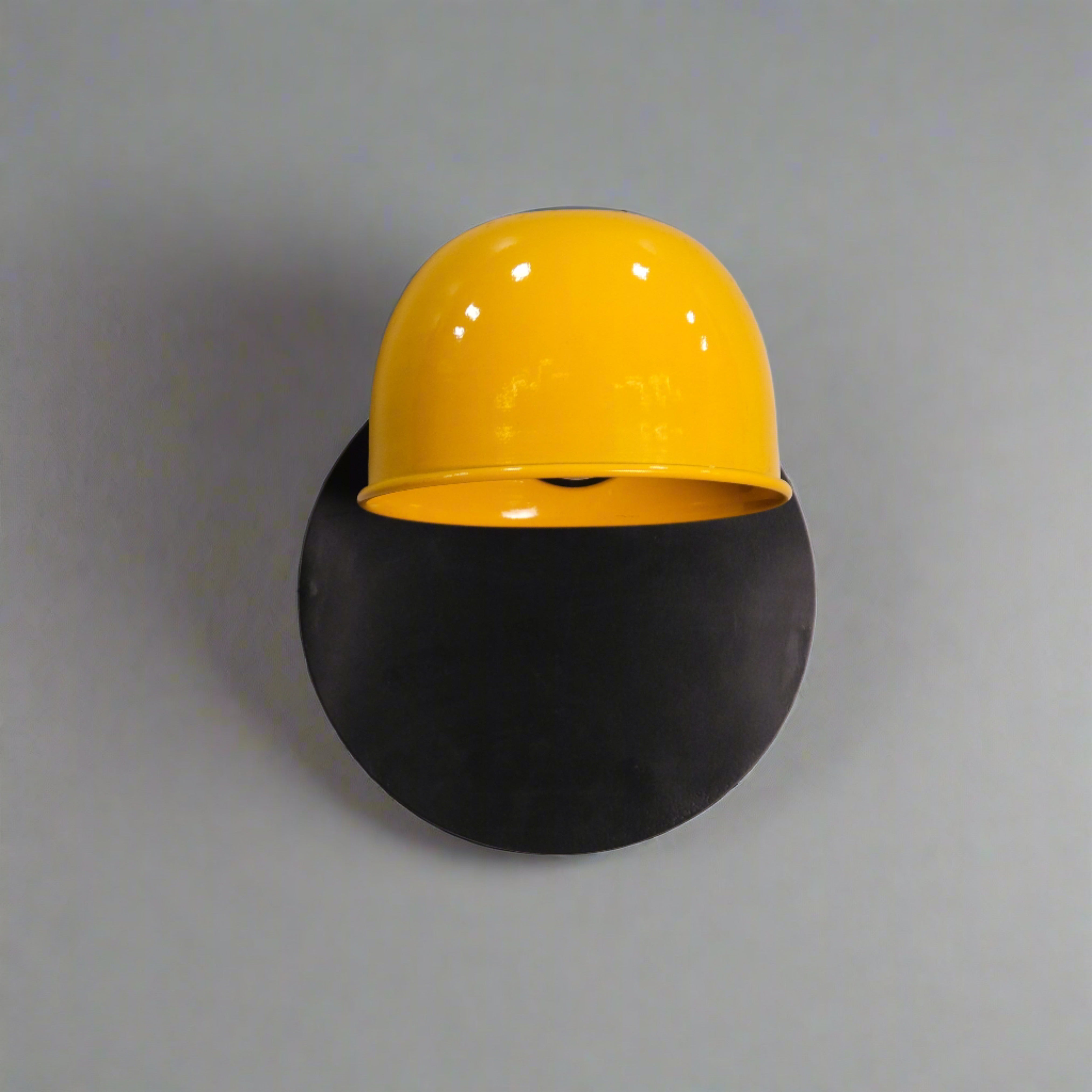 Affixed to a concrete wall, this sconce emits a warm glow from beneath the dome, creating an inviting ambiance.