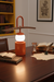 Desk lamp on a wooden desk with books and stationery items.