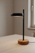 Modern table lamp with wooden base and black adjustable head on a light surface.