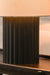 Table lamp with a black base and peach-colored shade on a wooden surface.