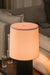 Black Table lamp with a beige shade on a wooden side table in a living room setting.