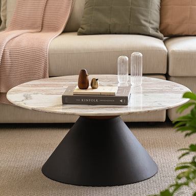 Minimalist marble coffee table with solid black base with books and decorative items.