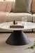 Minimalist marble coffee table with solid black base with books and decorative items.