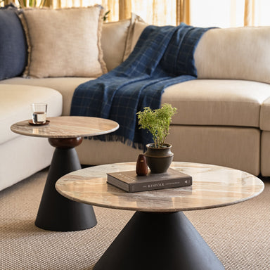Round marble coffee table and accent table nested with matte black bases styled with books and plants.