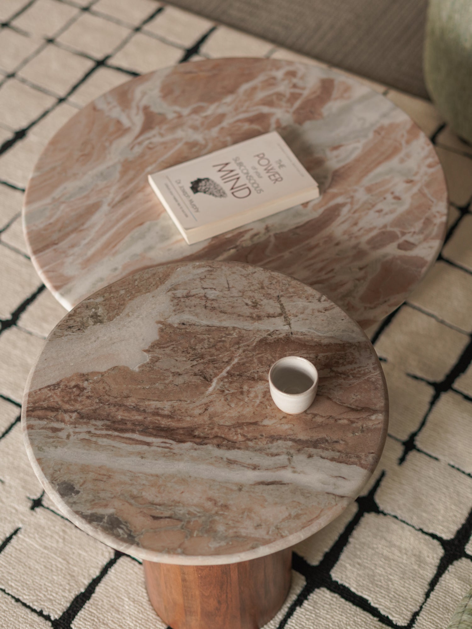 Round marble coffee table with a book and a cup on a patterned rug