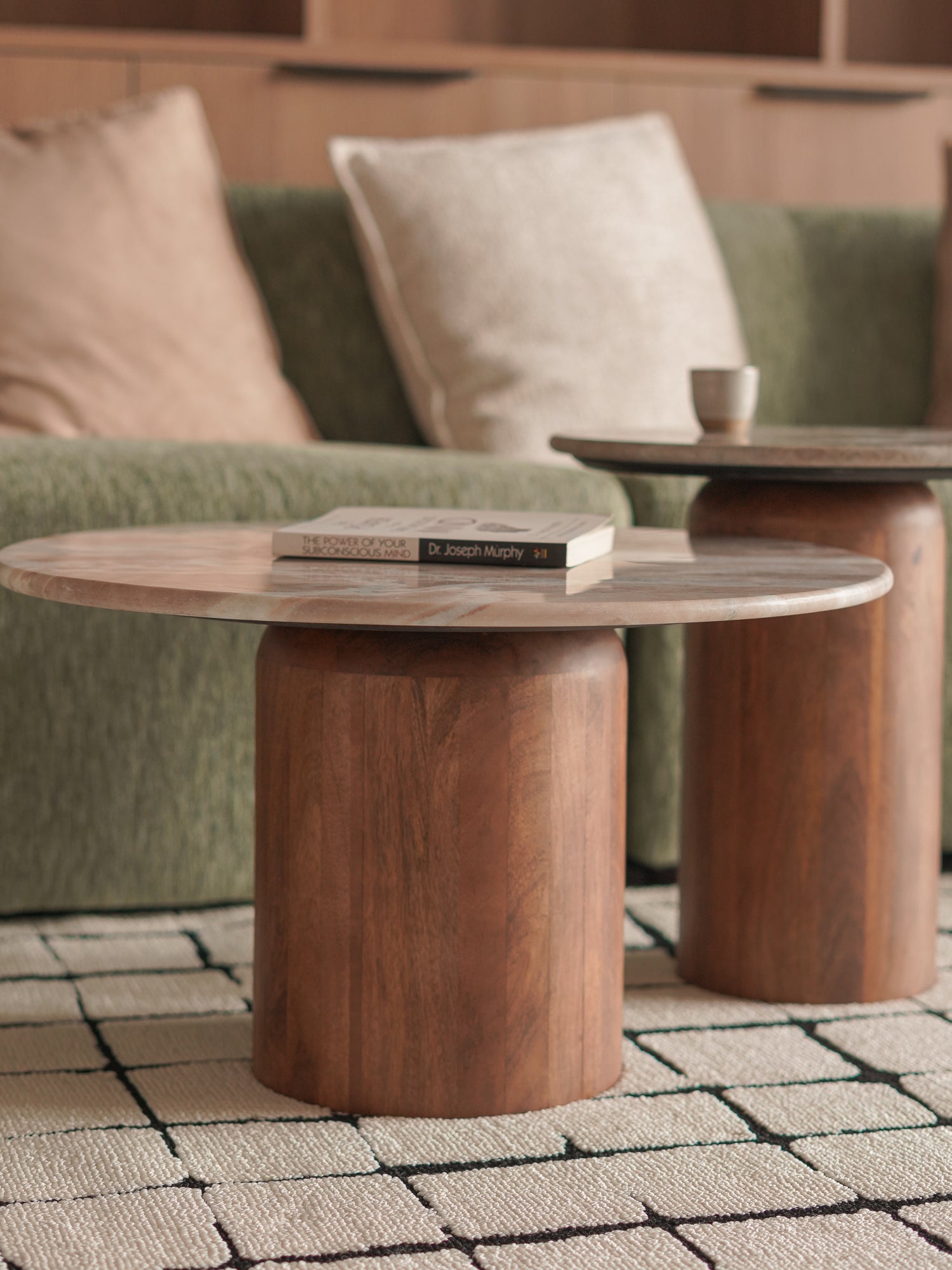 Wooden coffee table with a book on a green sofa in a living room setting