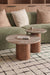 Two wooden coffee nesting tables in front of a green sofa with beige cushions on a tiled floor.