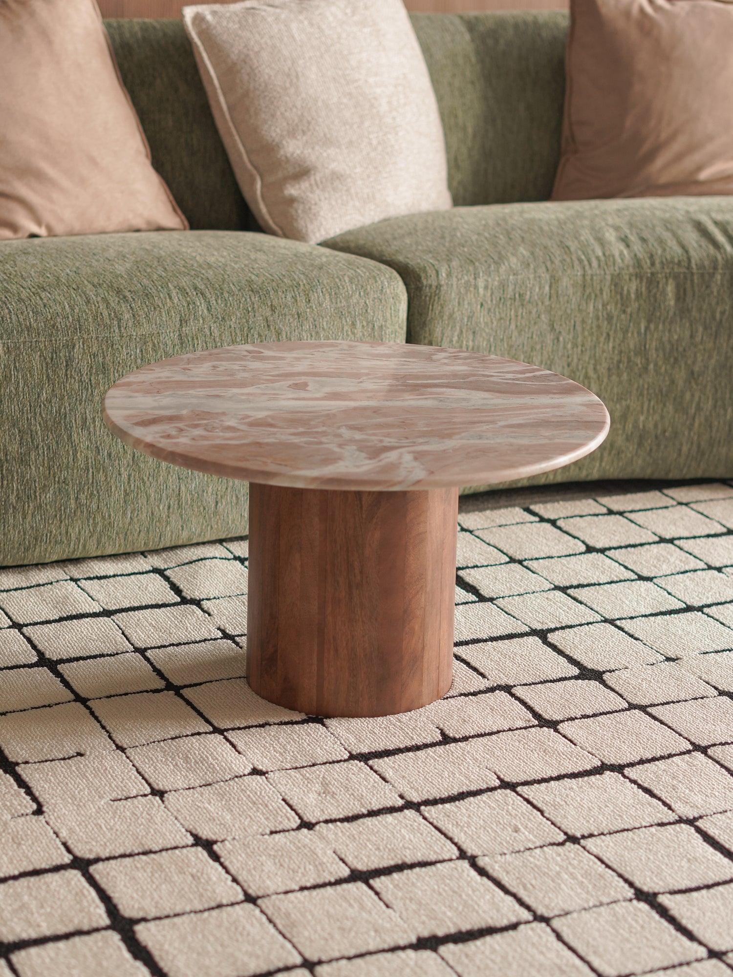 premium marble and wood coffee table in front of a green sofa on a patterned rug