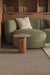 Green sofa with wooden side table and books on shelves in a room.