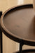Close up of the round wooden side table with black metal frames.