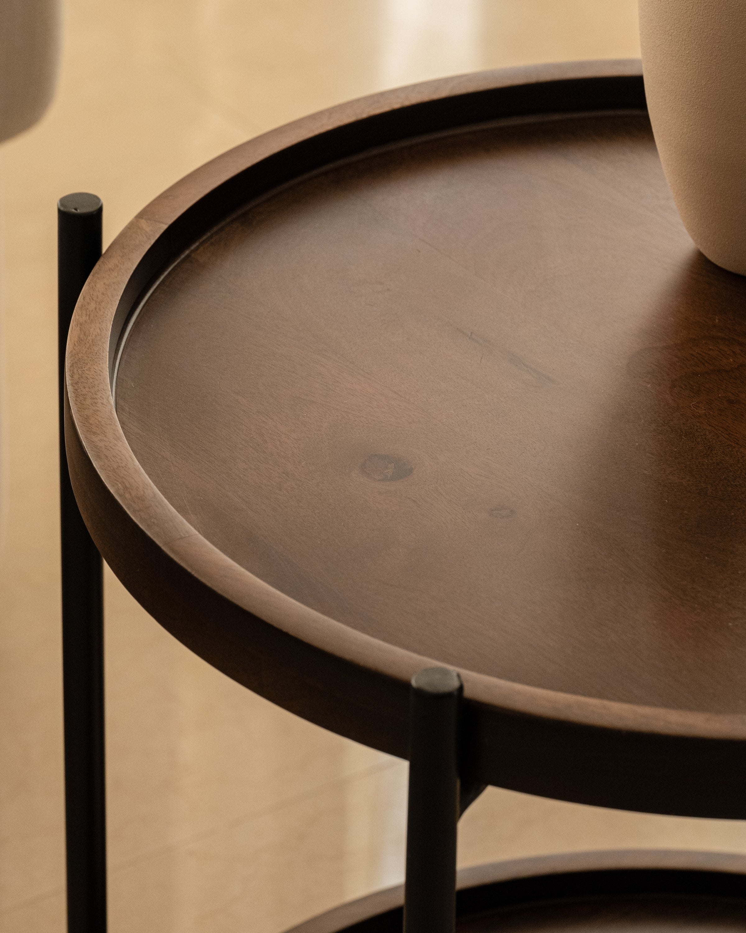Close up of the round wooden side table with black metal frames.
