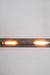 This modern lighting solution features an elongated glass tube encasing two glowing filament bulbs