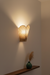 Wall-mounted lamp with checkered shade casting light on a plain wall.