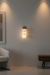 Wall-mounted light fixture in a modern room with a sofa and side table.