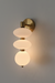Wall-mounted light fixture with three glass shades on a gray wall.
