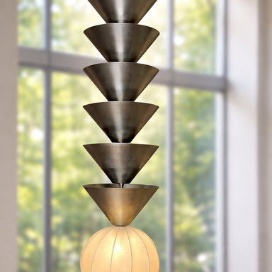 Modern pendant light with tiered design in a room with large windows.