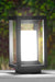 Black outdoor lamp with a white light on a blurred green background