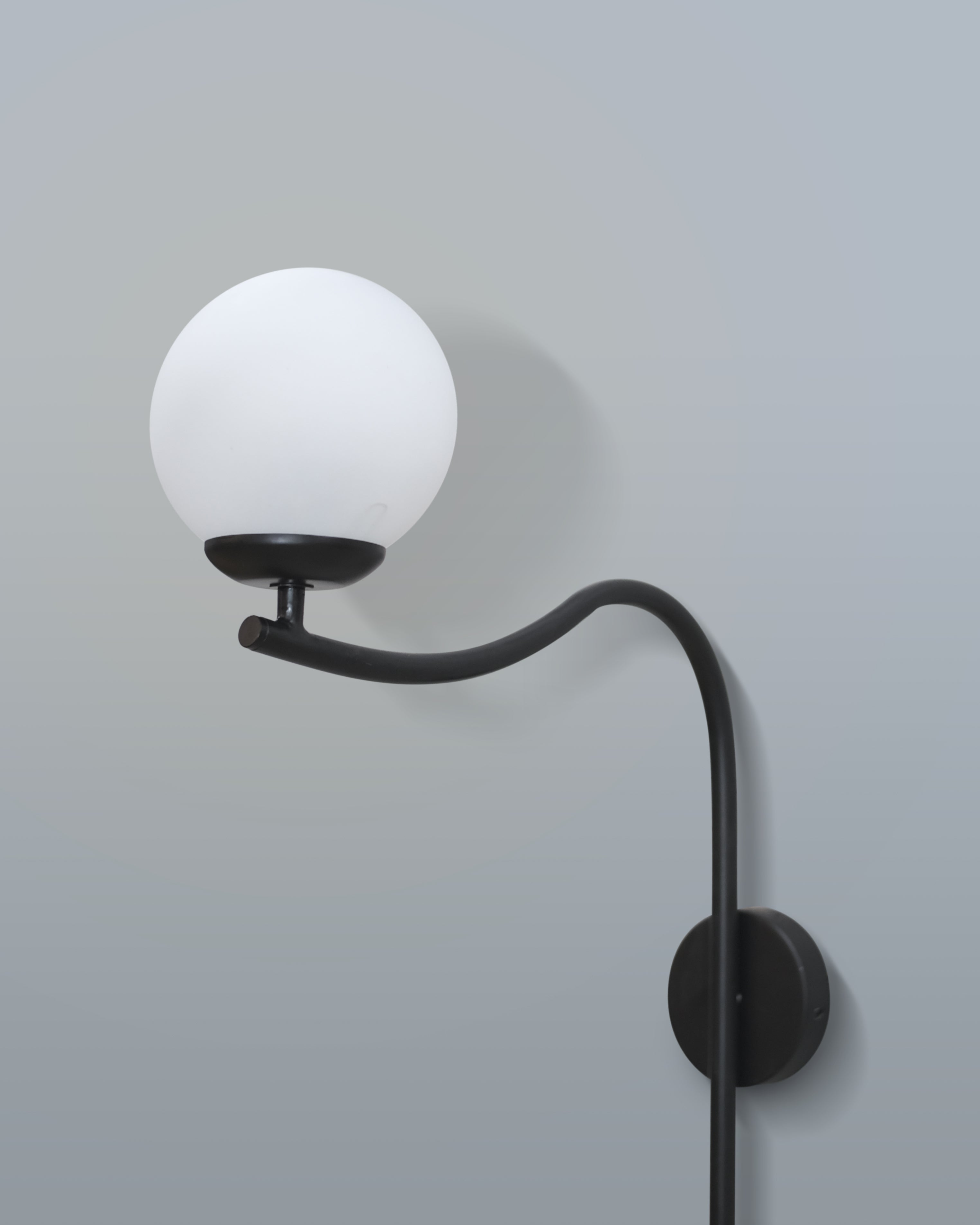 Contemporary arched wall lamp with a sleek black design and a soft-diffused white lampshade, mounted in a living room