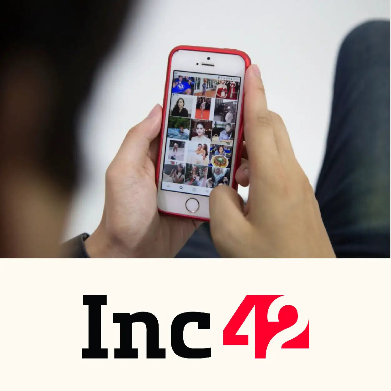 Red iphone 5s with a glossy finish and rounded edges, held in hands displaying its screen filled with photo thumbnails.