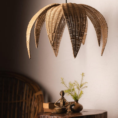 Wicker palm leaf pendant light hanging above a wooden table with decor items.