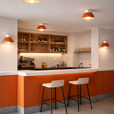 Modern kitchen with orange and white color scheme, featuring bar stools and a counter.