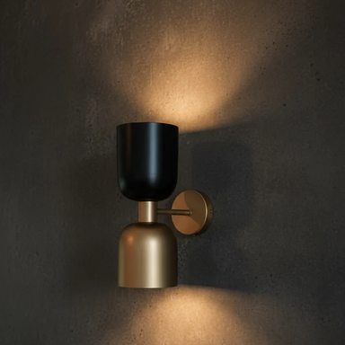 Wall-mounted light fixture with black and gold design on a dark wall.