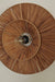 Decorative wall light fixture with woven design on a plain wall.
