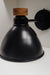 Modern black wall lamp featuring a conical shade and a wooden accent knob, mounted on a horizontal arm and round base. Ideal for adding a touch of elegance and functionality to any room.