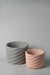Large gray and small pink prickly concrete planters